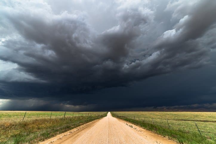 A dirt road under a stormy sky.