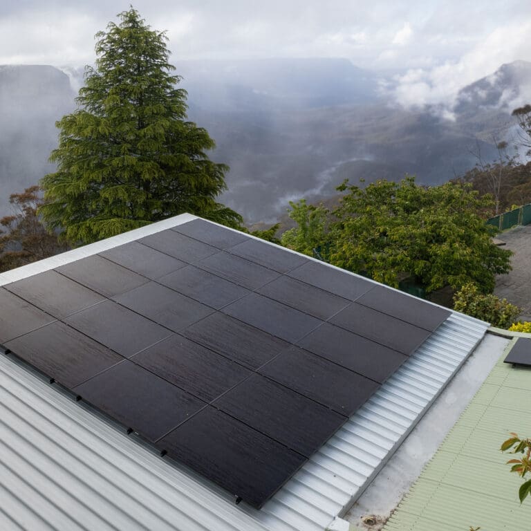 Solar panels on the roof of a house with mountains in the background.