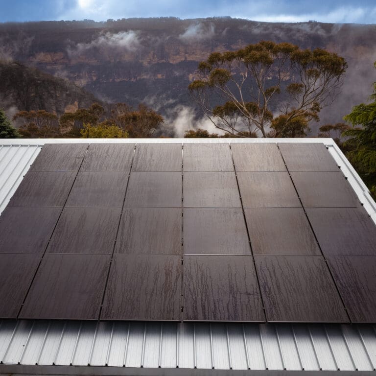 Solar panels on a roof with mountains in the background.