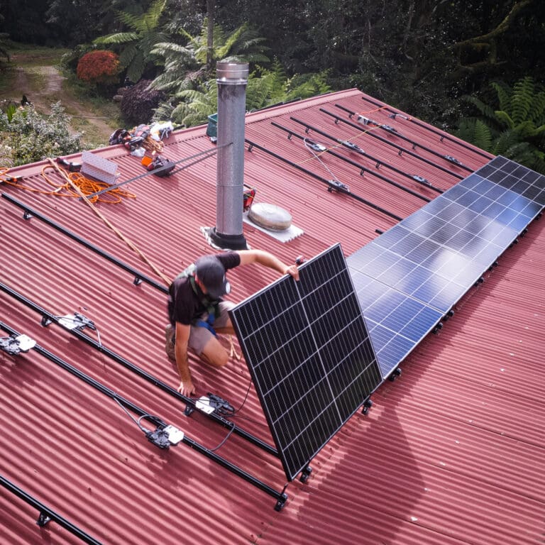 A man installing solar panels on a roof.