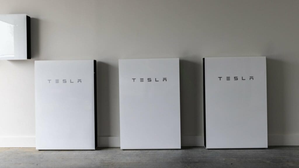 Three tesla chargers are lined up against a wall.