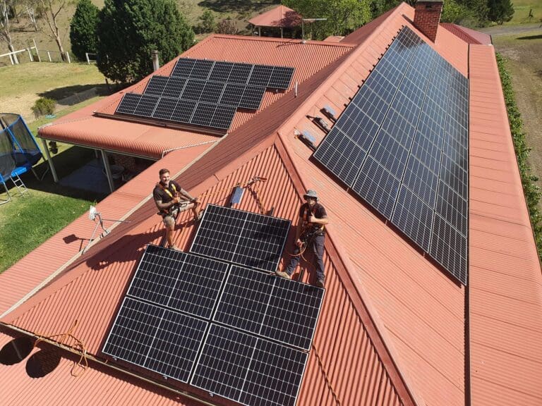 Two men on a roof installing solar panels.