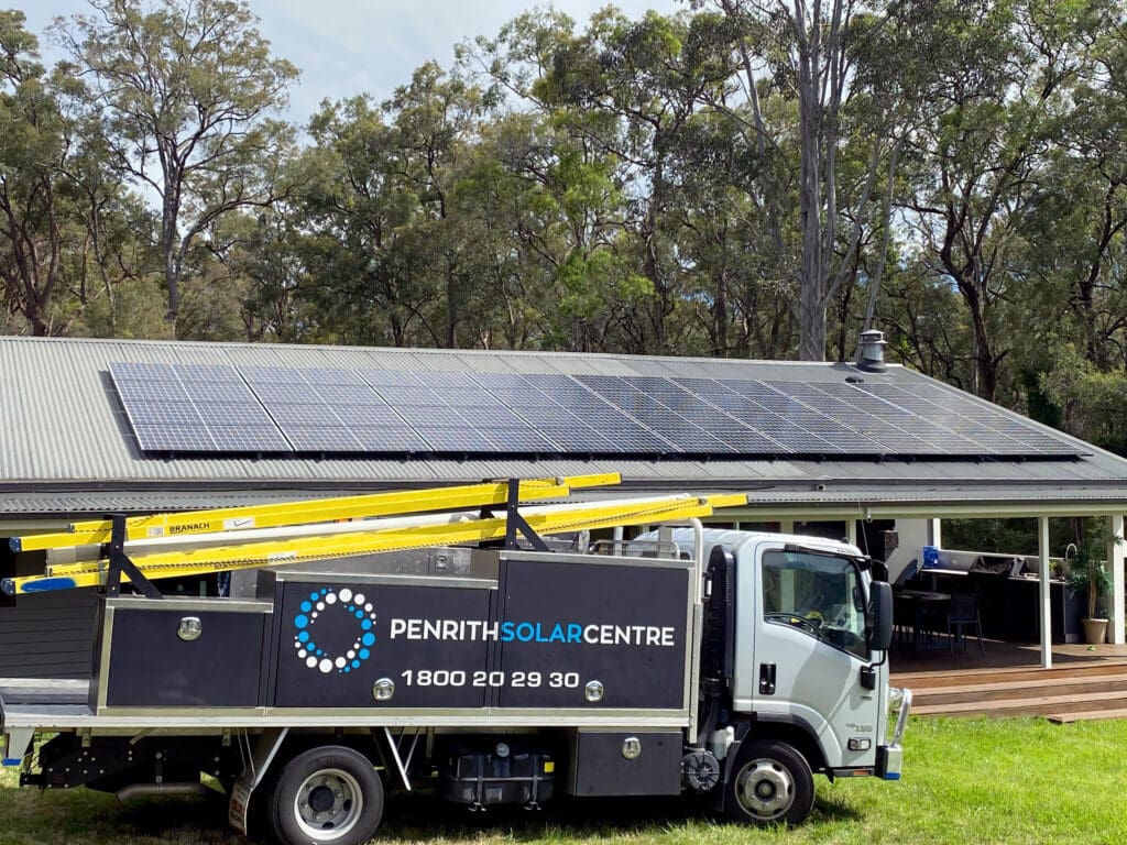 A truck parked in front of a house with solar panels on the roof.
