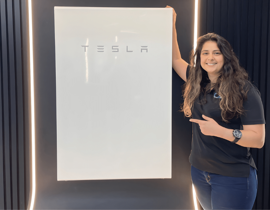 A woman standing next to a tesla sign.
