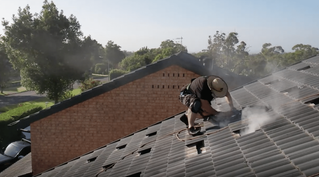 A man is cutting tiles on the roof of a house.