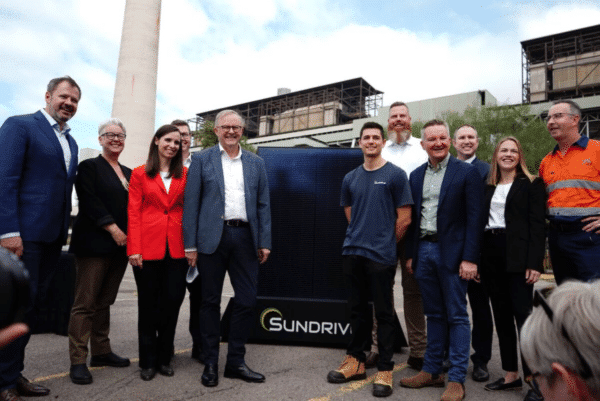 Group of individuals posing with a solar panel at an outdoor event.