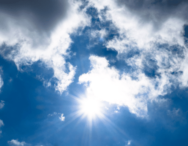 Sun shining brightly in a blue sky with scattered clouds.